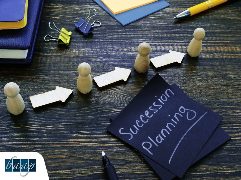 Succession planning concept with wooden figures and arrows on desk at B.A.A.P.